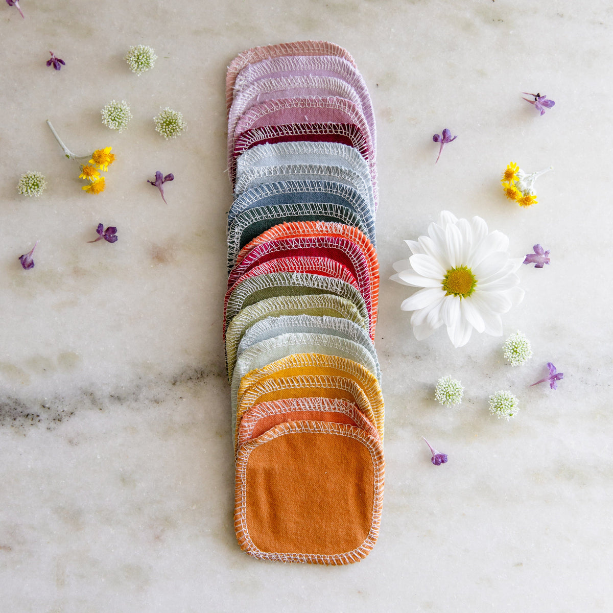 Rainbow colored reusable cotton rounds displayed in a long line