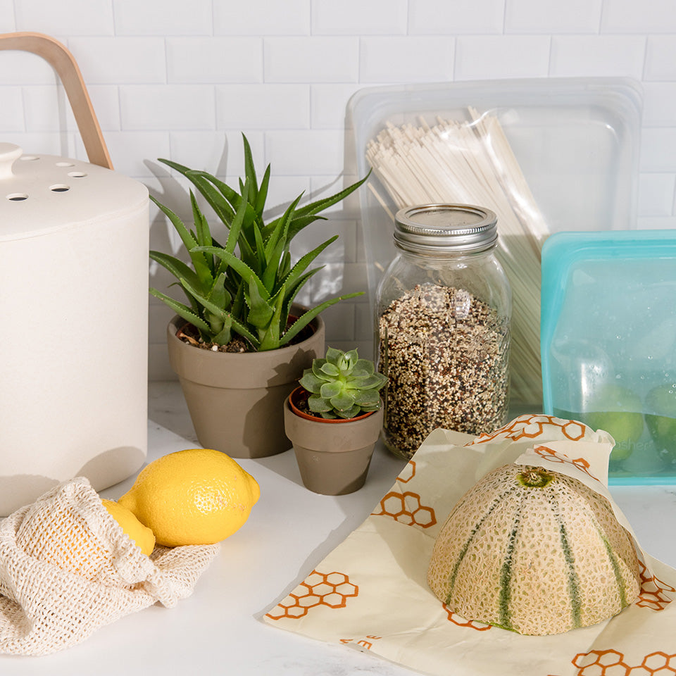 Beeswax wrap, mesh produce bag, glass jar, and stasher bags on a kitchen counter