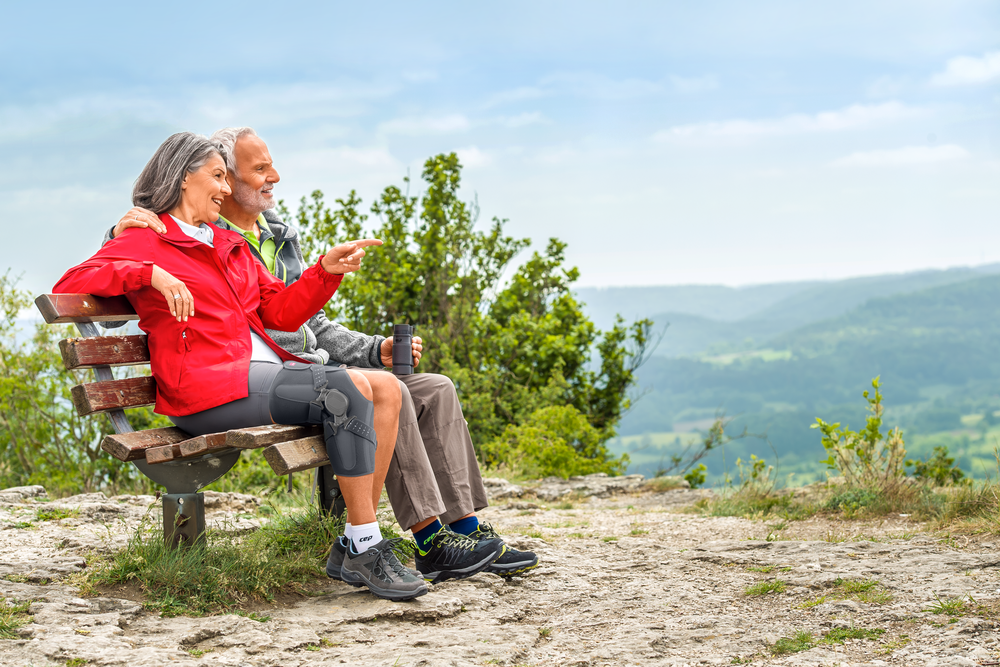 Two older people resting on bench during hike