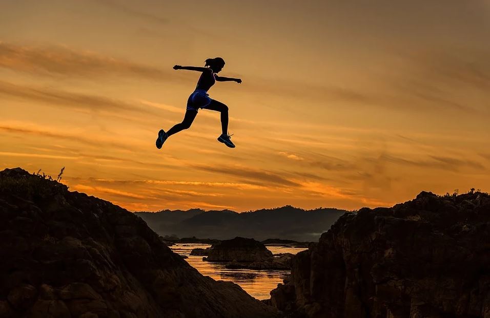 woman leaping over gap at dusk