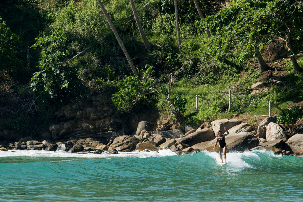 Woman doing a cheater five on single fin longboard wearing a surf bikini in Sri Lanka