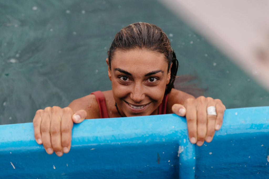 Woman smiling from the water and holding on the railing of a fishing boat