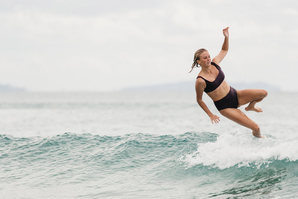 Woman falling off her surfboard wearing the mason surf bikini top and kennedy surf bikini bottom