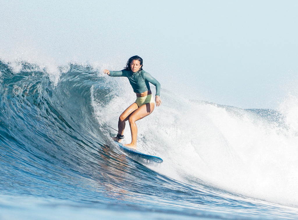 Erika surfing wearing a rash guard and lucky high waisted surf bikini bottoms 