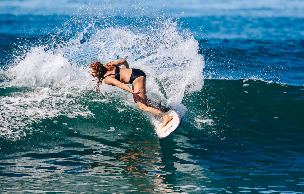 Woman doing a cutback on shortboard wearing a black surf bikini