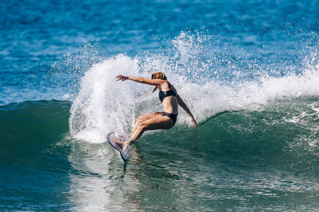 Woman doing a cutback on shortboard wearing a black surf bikini