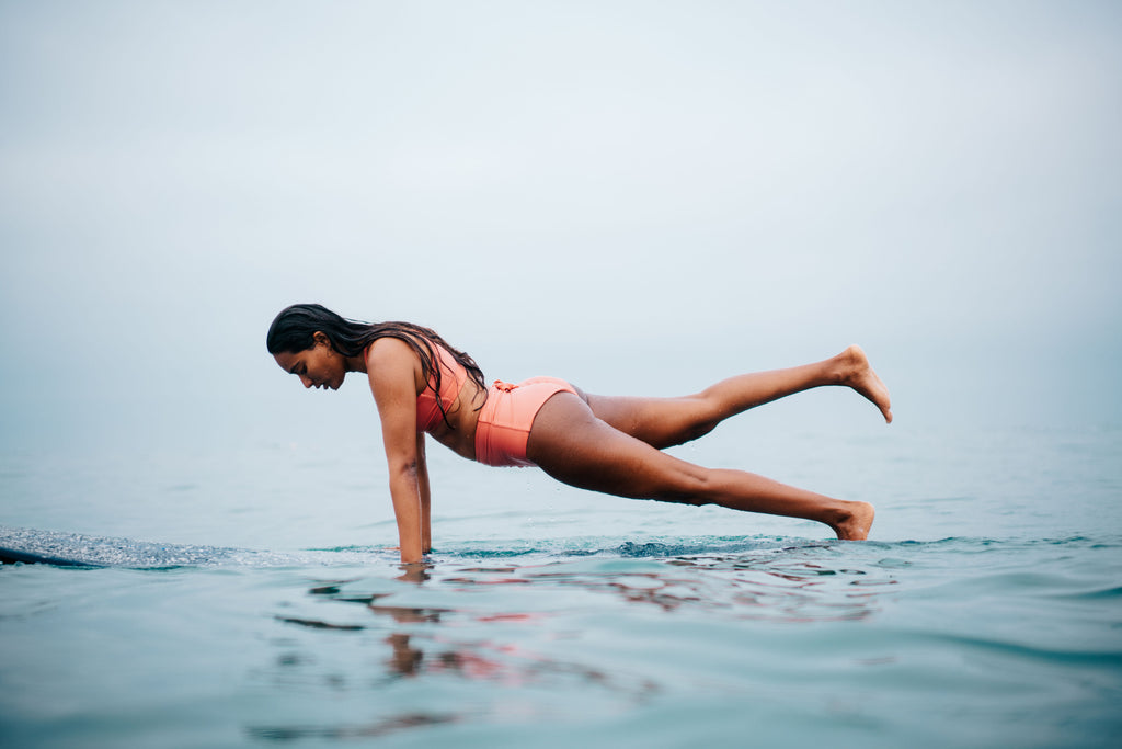 Woman in pink bikini pushing up on her longboard