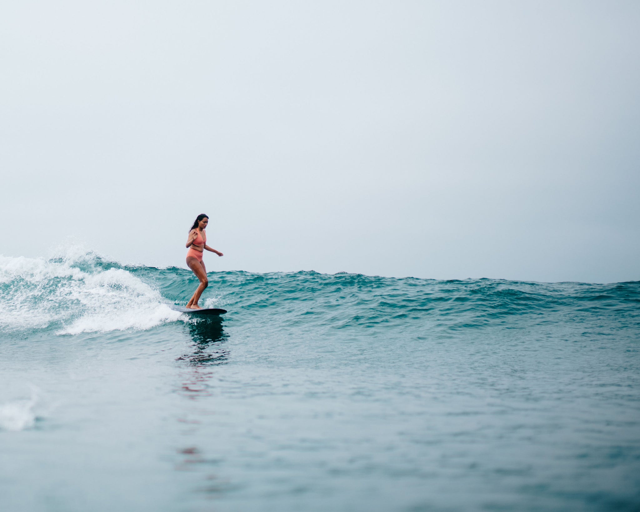 ヴィンテージの赤面ビキニでロングボード サーフィンをする女性