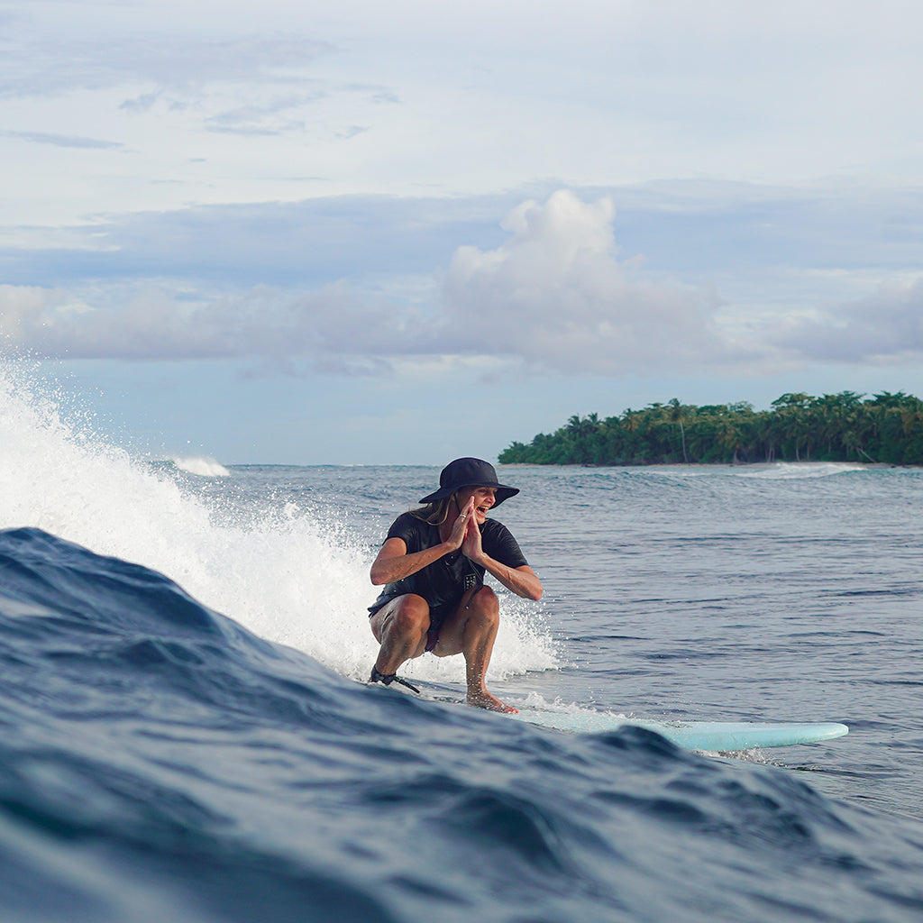 Woman surfing the waves, wearing SEPTEMBER The Line sustainable surf and swimwear.