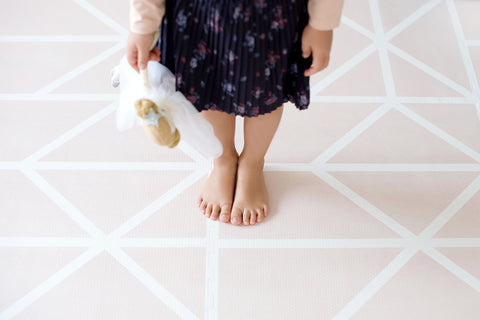 jeune fille aux pieds nus debout sur un tapis de jeu