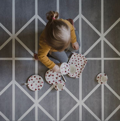 Jeune fille assise sur un tapis de jeu ayant un thé imaginaire