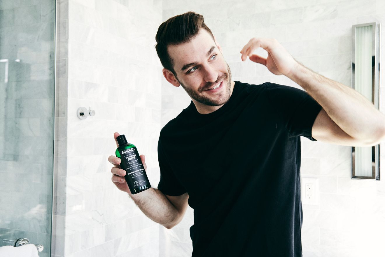 Man holding shampoo in bathroom