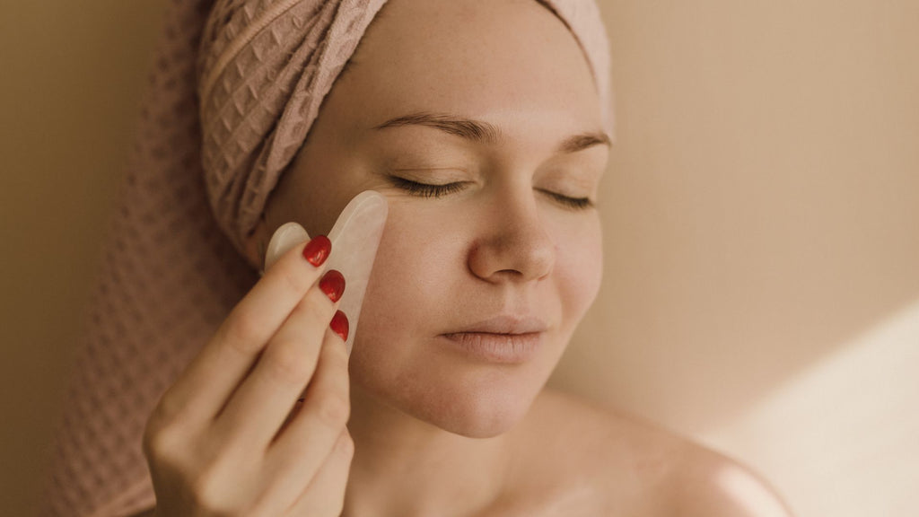 Woman doing facial massage with Gua Sha to help relax for better sleep