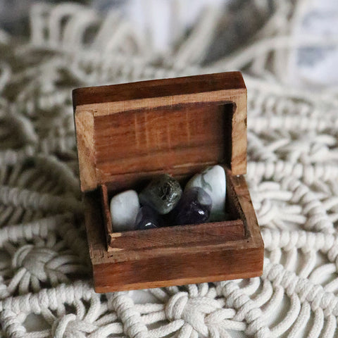 A tiny wooden box with tumbled Amethyst, Labradorite, and Moonstone inside