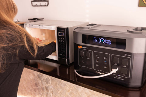 woman opening a microwave that is connected to a solar generator