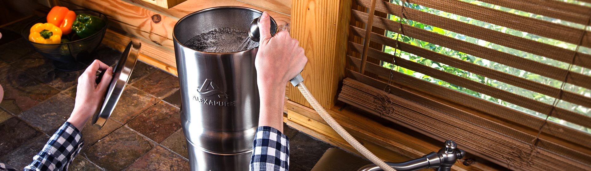 Alexapure Pro gravity fed water filtration system being filled on the counter