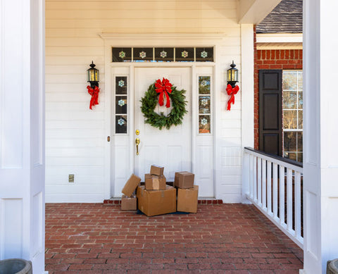 brown packages in front of a porch door with a Christmas wreath