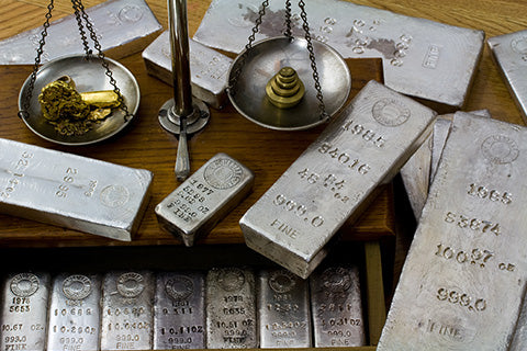 A bunch of solid silver bars and a scale on a table.