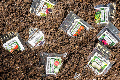 Patriot Seeds seed packets scattered around in a pile of dirt.