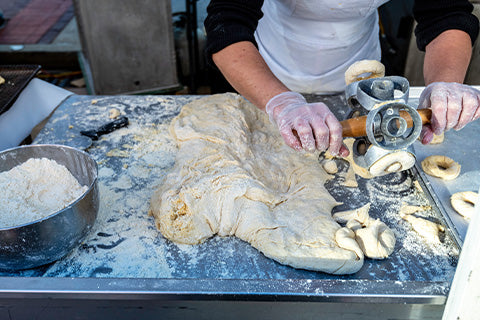 A person using a hand-powered tool to work with dough in a kitchen.