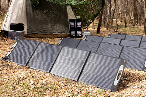 A group of solar panels spread out near a tent and stack of emergency food.