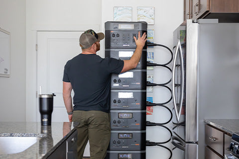 A man connecting a stack of generators on top of one another in an indoor kitchen.