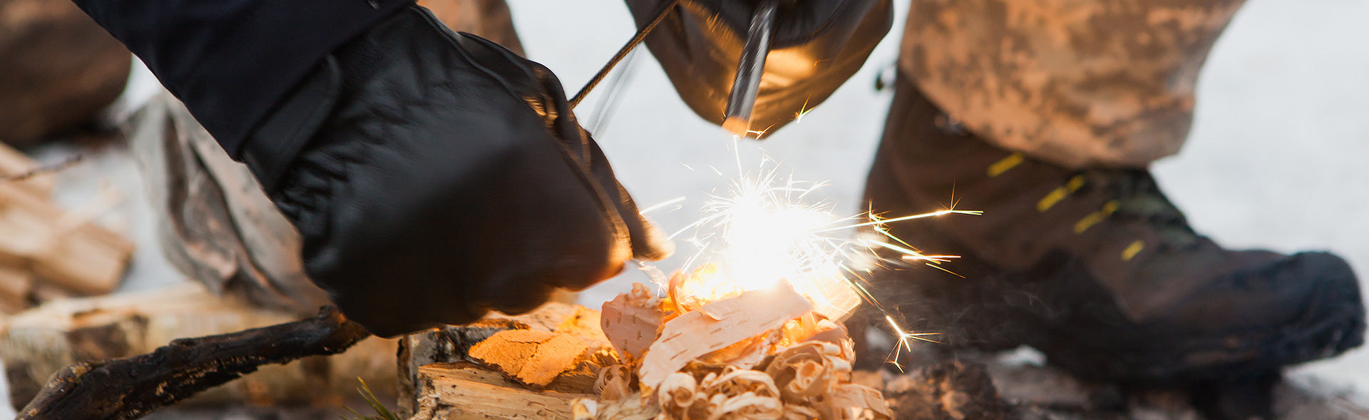 A ferro rod sparks as it ignites the dry tender on the frozen ground