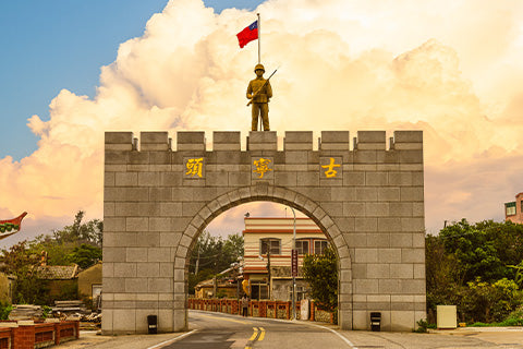 An arch in Taiwan with a statue of a soldier on top with the flag.