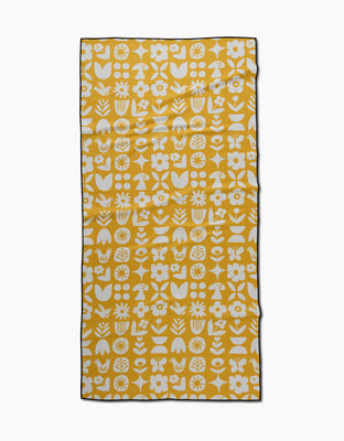 The Scandi Spring beach towel by Kayla Ann is yellow and rectangular, with white flowers, leaves, butterflies, mushrooms, and florals in a repeating pattern plus a thin black border—made from quick-drying recycled materials.