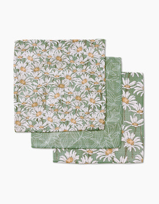 Three folded Springtime cloth napkins by Aubrey Fairchild, crafted from super-absorbent Geoweave fabric, display a green background with white daisy patterns and are stacked slightly offset.