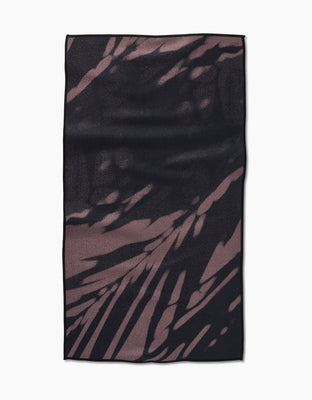 The GEOMETRY Palm Shadow Fitness Towel is rectangular, ultra-absorbent Geoweave fabric with a dark brown and black abstract palm leaf pattern, shown flat on a white background.