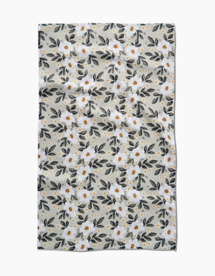 The Painted Spring Flowers Tea Towel by Teri the Butter is made from recycled Geoweave™ fabric. It features white flowers with yellow centers and green leaves on a light beige background, with a naturally wrinkled look.