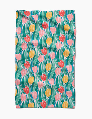 The Tranquil Tulips tea towel by Sarah Daugherty features a cheerful Geoweave fabric with pink, red, and yellow tulips and green leaves on a slightly textured light blue background.