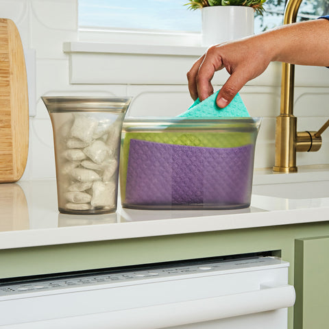 a kitchen counter featuring two Zip Top containers filled with dishwasher pods and reusable dish towels