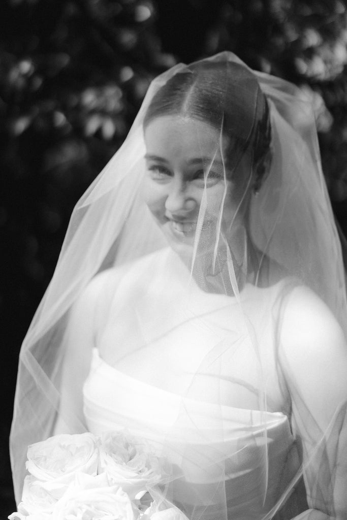 classic and clean bride in straight cut strapless gown and raw edge blusher wedding veil over face