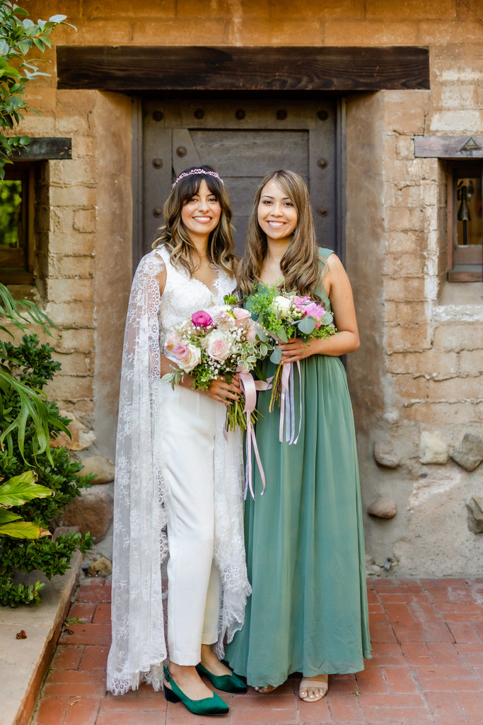 bohemian romantic bride in wedding pantsuit and Chantilly floor length lace cape with bridesmaid