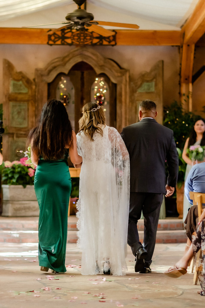 boho lace floor length cape on hipping bride walking down aisle in hacienda
