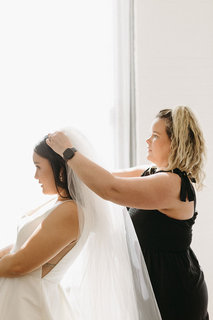 mom putting wedding veil with comb in hair for classic elegant bride