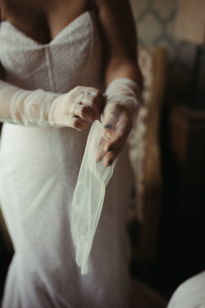 putting on white tulle wedding gloves before the ceremony