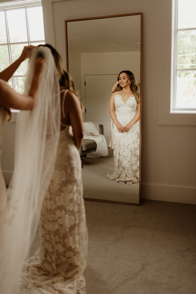 putting the cathedral wedding veil in the bride's hair after taking out wrinkles with a steamer