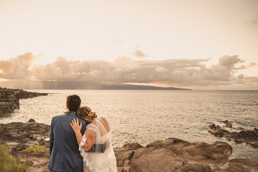 bride and groom facing beach sunset with bride in white lace elbow length bridal veil that shows off tattoo 