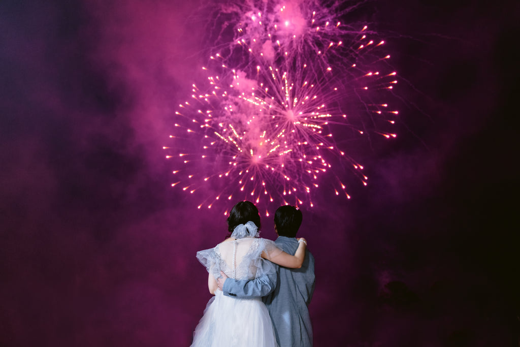 Disney fireworks in background as bride holds groom wearing pearl bridal bow over chignon