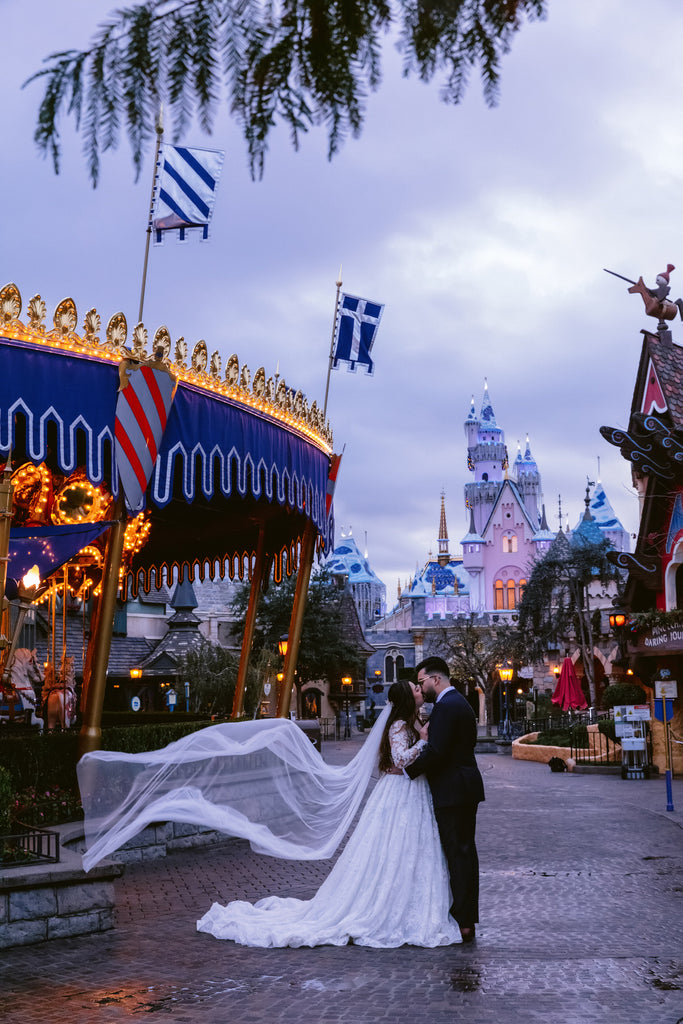 princess bride at Disneyland in long English net bridal veil in front of carousel 