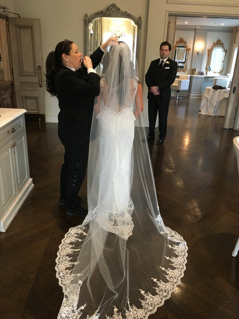 bride trying on a chapel length French lace bridal veil in salon