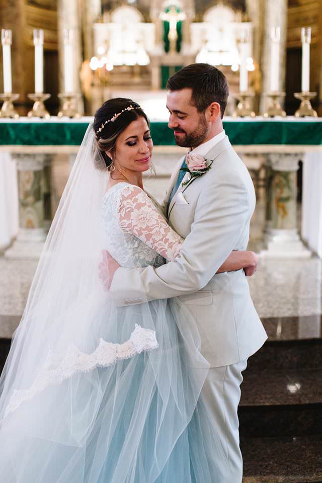 christian wedding with bride wearing blue wedding dress and long two layer lace cathedral bridal veil with updo