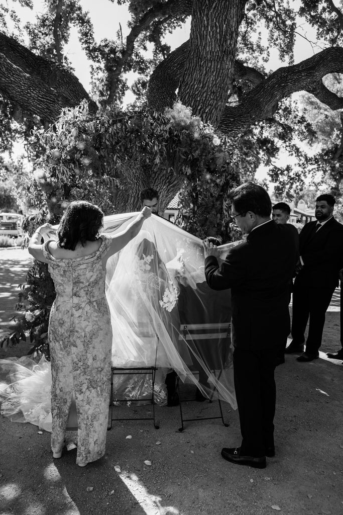 filipino bridal unity veil being placed over couple's shoulders for catholic service