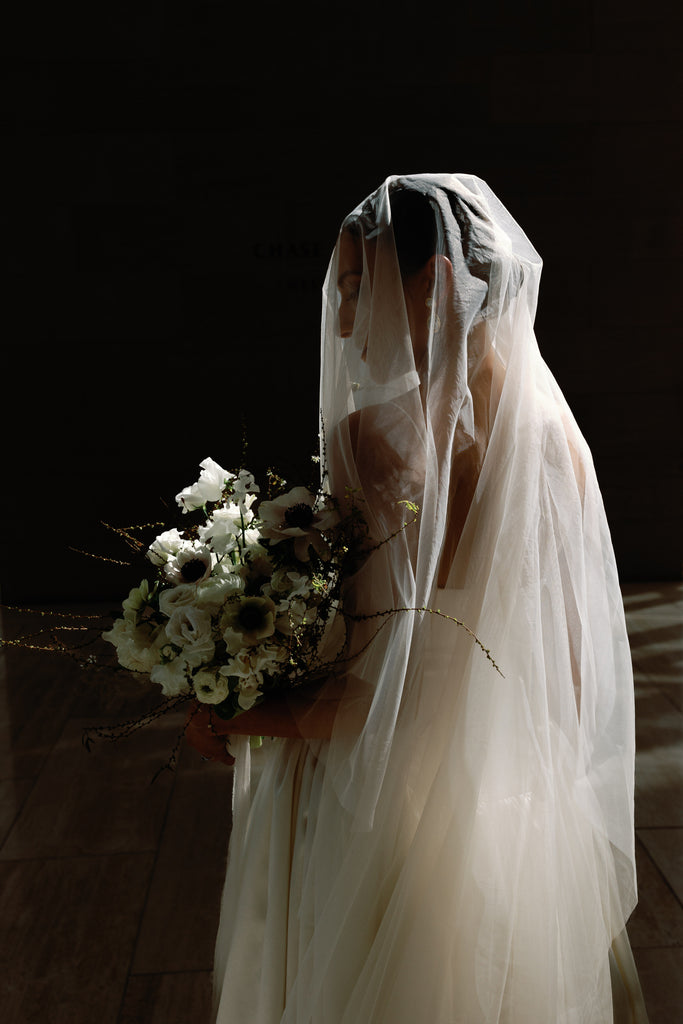 drop silk cascade wedding veil with raw edge over bride's sleek updo bun