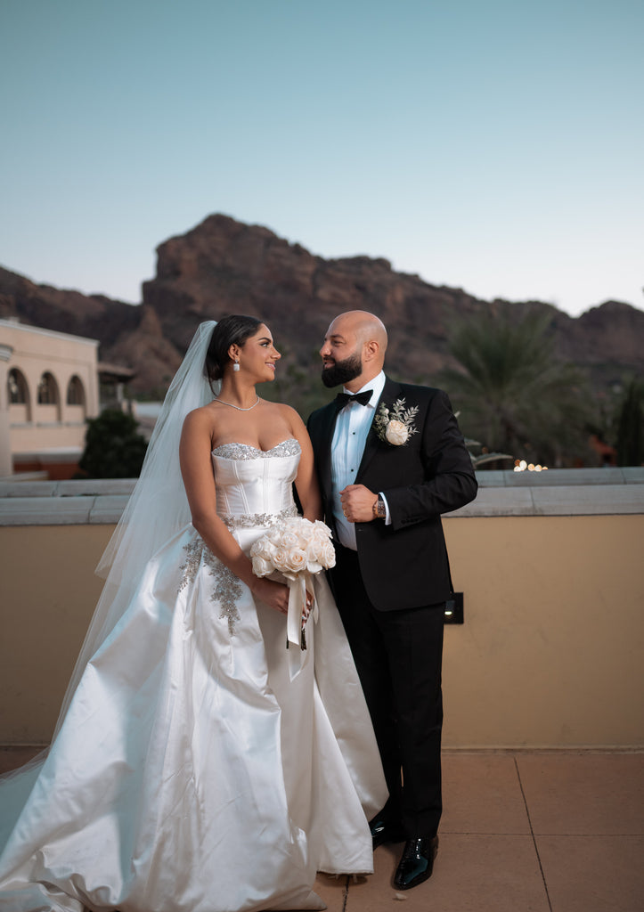 glam ballgown in satin with long royal length wedding veil with custom embroidery amid a desert resort backdrop