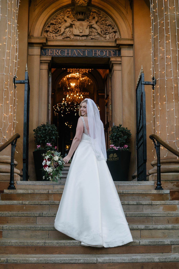 hotel resort wedding with glam bride in mid length embroidered trim wedding veil on staircase entrance