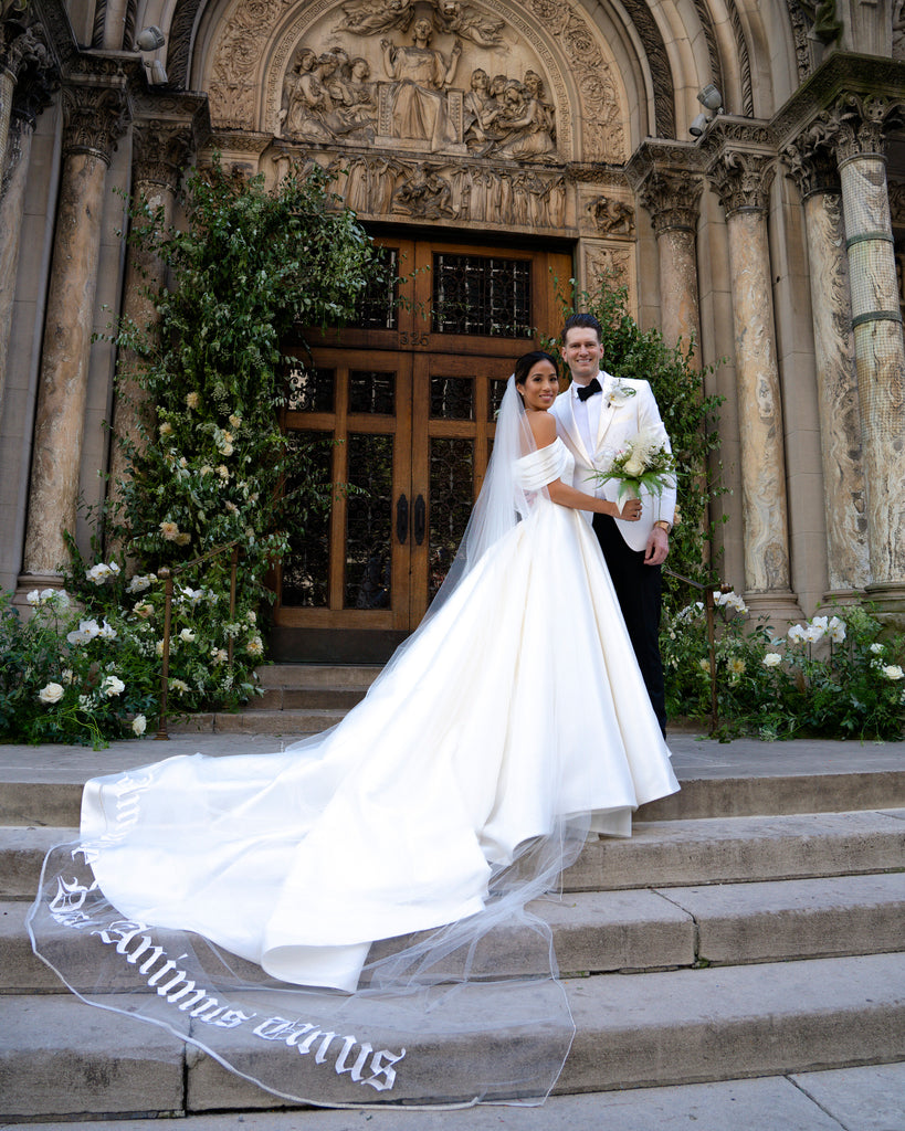 dramatic wide embroidered royal length wedding veil and satin ballgown draping down stairs in front of church